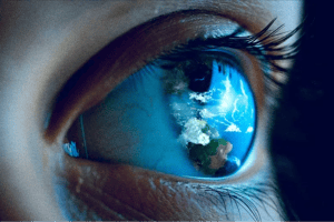 A close up detailed image of a woman's eye reflecting the earth in the iris, depicting foresight.